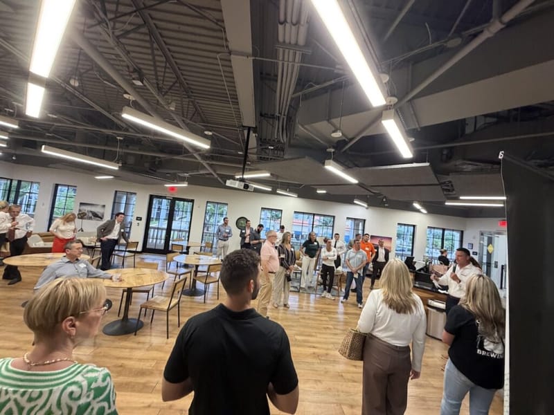 Networking event in a modern open venue with wood floors, groups of attendees mingling throughout the room